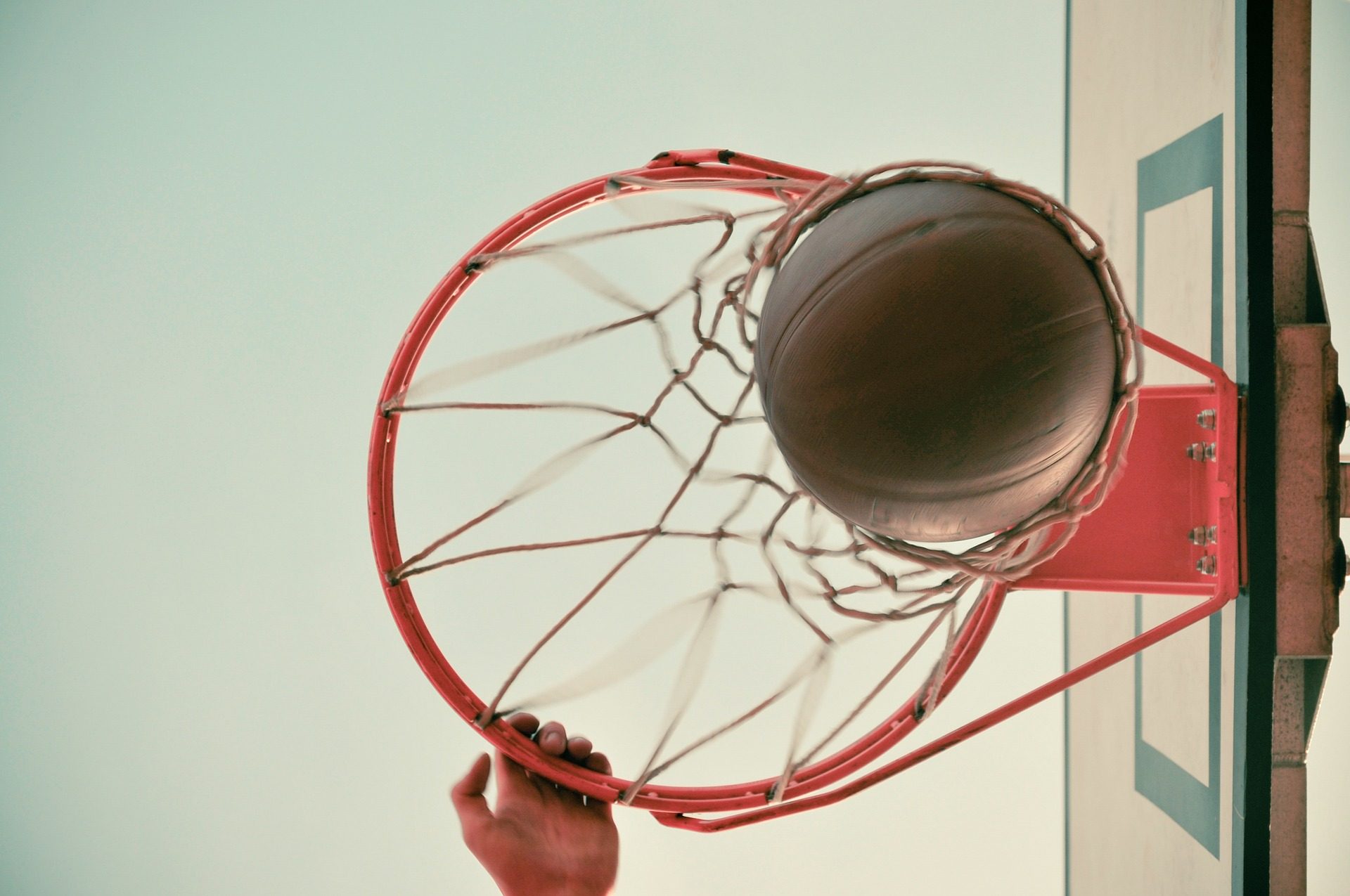 Ein Basketball Korb von unten, ein Ball fällt durch